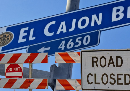 Composite photo of the "El Cajon Bl." road sign and road closure signs below.